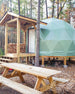 Geodesic dome structure with wooden deck and picnic table in a forest setting